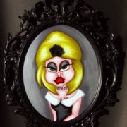 Figura femminile stilizzata con capelli gialli, abito nero e cornice barocca nera in stile Pop Art.