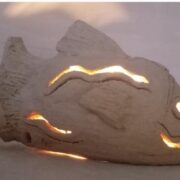 Scultura a forma di pesce con luce interna che filtra da aperture decorative