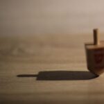 Sevivon fotografato in modo sfocato su una superficie di legno, con una marcata ombra proiettata dalla luce laterale.